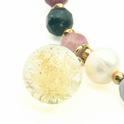 Zbliżenie na zawieszkę z żółtej żywicy z zatopionym dmuchawcem – detal bransoletki.