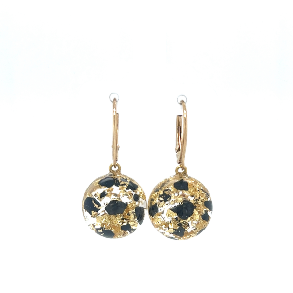 Kolczyki z czarnej żywicy z złotymi akcentami w kształcie okrągłych płatków, zawieszone na złotych biglach.