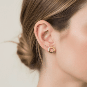 Złote minimalistyczne kolczyki w uchu modelki.