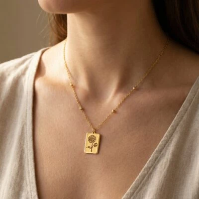 A close-up of a gold necklace featuring a floral design, worn by a woman.