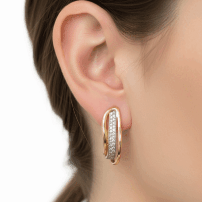 Złote kolczyki z potrójną falą i cyrkoniami na uchu.