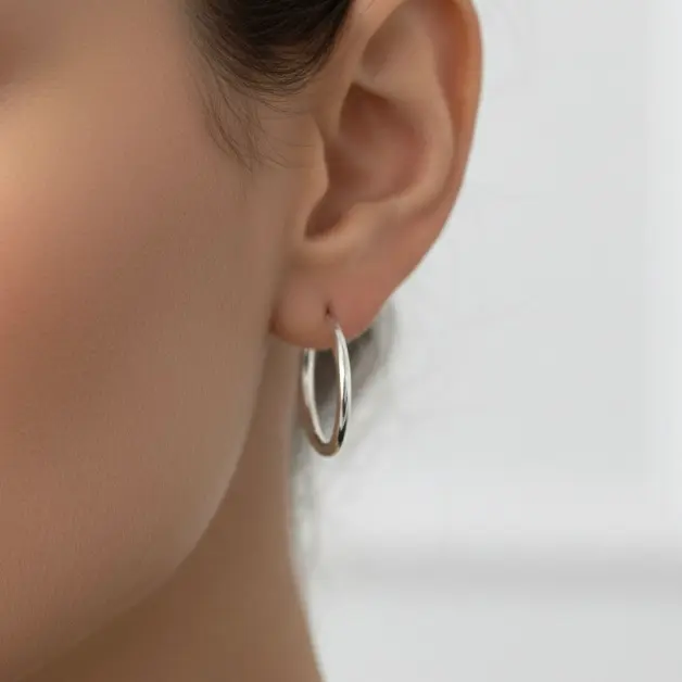 Earrings in the shape of thin hoops worn by a model.
