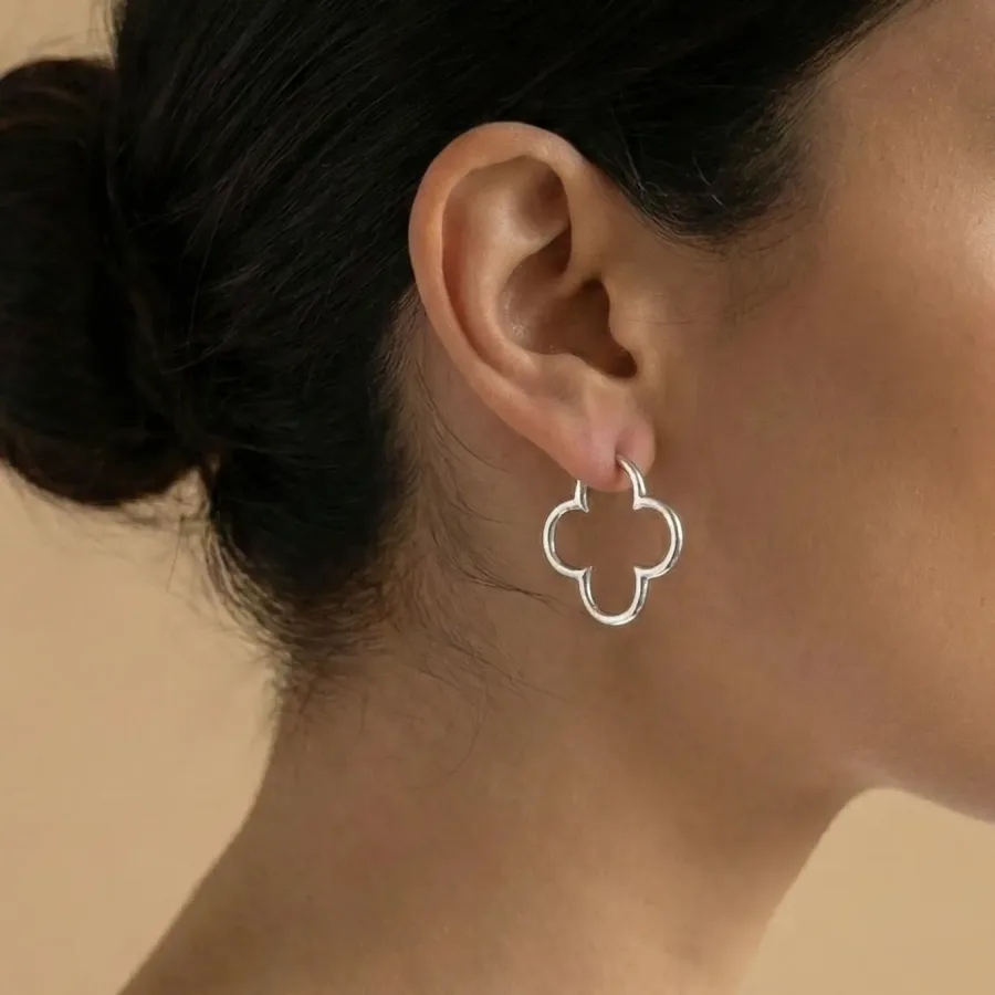 A model showcasing silver clover-shaped earrings.