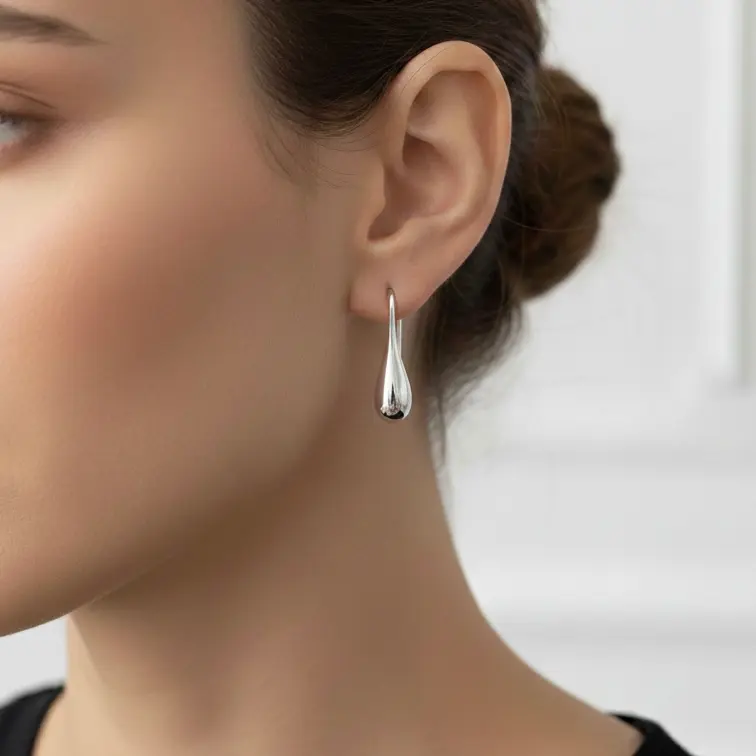Kolczyki wiszące w kształcie kropli na uchu modelki.