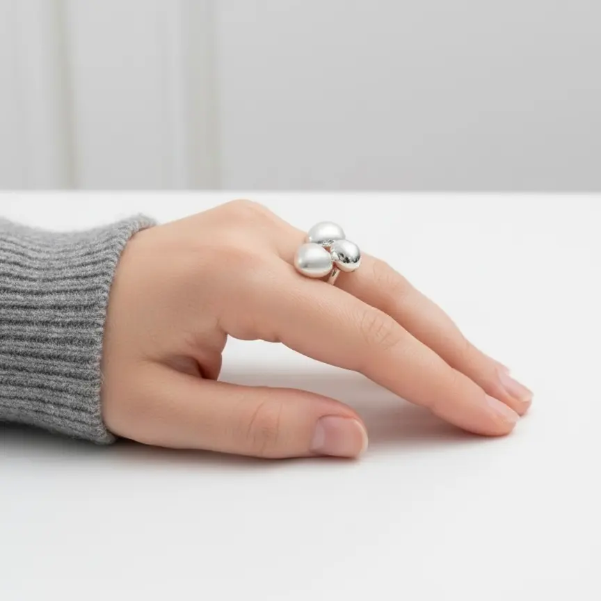 Srebrny pierścionek z trzema kulkami na dłoni